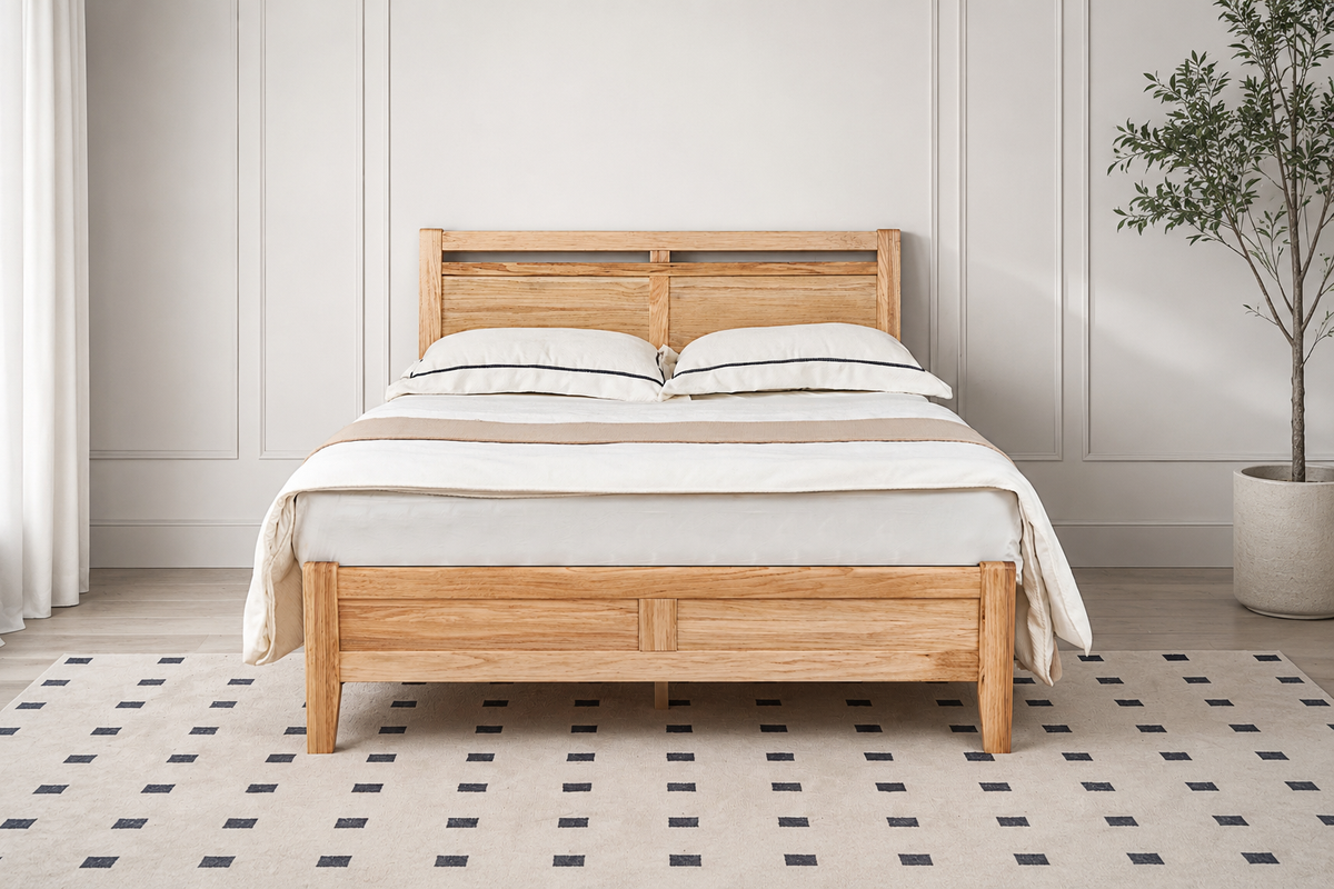 A light natural wood bed frame with a slatted headboard and footboard, styled with white bedding and pillows in a bright, modern bedroom setting with a patterned rug and a potted plant.