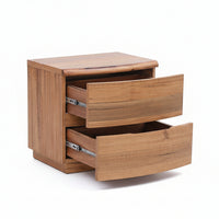 Wooden drawer unit with two drawers open on a gray floor against a gray wall.