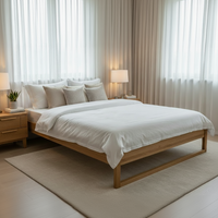 A modern wooden bed frame with white bedding and multiple pillows, styled in a bright, minimalist bedroom with matching nightstands, lamps, and sheer curtains.