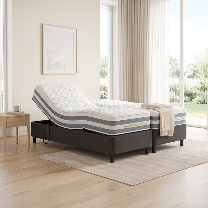 An adjustable electric motorized bed frame with a white quilted mattress, shown in a bright, modern bedroom setting with light wood floors, beige walls, and large windows.